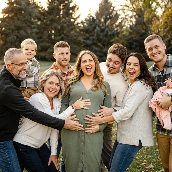 Familia extendida abrazando a la madre embarazada